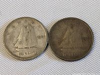 Two 1944 Canadian silver quarter coins, one lighter in tone and the other darker, placed side-by-side on a white textured surface.