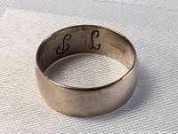Antique sterling silver band ring, close-up interior view showing engraved initials 'J L' and hallmark stamp indicating silver purity.