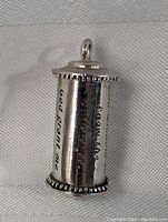 Image of pendant showing part of the Serenity Prayer engraved on the curved surface with decorative beaded edges on top and bottom.