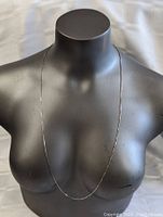 Front view of the long sterling silver box chain necklace displayed on a black mannequin bust.