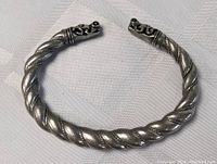 Front view of open cuff bracelet showing twisted rope design and end caps.