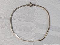 Full view of the sterling silver flat herringbone chain bracelet showing its length and clasp.