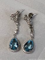 Close-up of both sterling silver drop earrings showing aqua blue quartz teardrop stones surrounded by clear stones with additional clear stones along the drop.