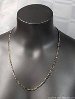 Front view of gold tone carved linkage necklace displayed on black bust.
