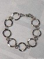 Full view of the sterling silver hoop bracelet laid flat to show entire design and clasp.