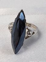 Close-up front view of the sterling silver ring with large black marquise-shaped faceted stone, showing ring setting and stone shine.