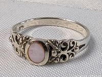 Close-up photo of sterling silver ring with pink quartz stone and intricate floral filigree detailing on the band.
