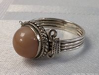 Close-up image of vintage sterling silver ring featuring a round brown stone and intricate silver rope and braided design details on the bezel and band.