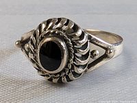 Front and top view of the ring showing the black stone and twisted rope silver setting.