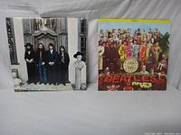 Two Beatles vinyl album covers displayed upright side by side, Sgt. Pepper's on right, Hey Jude on left.