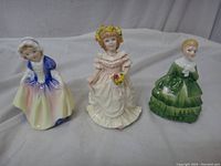 Front view of three Royal Doulton figurines: Dinky Do, Flower Girl, and Belle