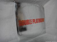 Silver embossed gatefold album cover with orange text "DOUBLE PLATINUM" showing on front.
