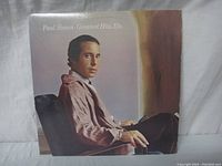 Front cover of the vinyl record album showing Paul Simon sitting in a chair with the title 'Paul Simon Greatest Hits, Etc'.