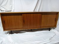 Front view showing full-length bench with three sliding doors and metal legs