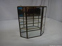 Vintage miniature curio cabinet empty showing glass panels, brass trim, and mirrored back.