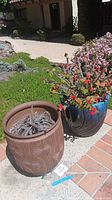 Two planters side by side on patio showing blue glazed and brown textured pots with succulents