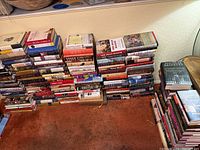 Stacked piles of mostly hardcover books on history with some paperback editions visible, photographed from a standing angle showing titles and covers.