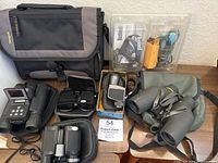 Full view of lot including Targus bag, multiple binoculars, a monocular, and green soft case