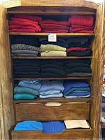 Full cabinet view showing folded sweaters on four shelves and two drawers.