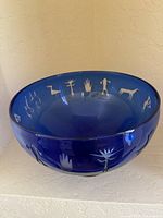 Front view of cobalt blue glass bowl displaying etched petroglyph designs on the outside rim
