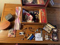 Overview of lot on wooden surface: wooden and metal boxes, silk bow tie, assorted cufflinks, tie tacks, pins, folding pocketknives
