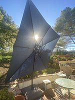Open square navy blue canopy mounted on offset cantilever pole over outdoor patio