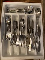 Flatware arranged in drawer insert showing spoons, forks, knives and utensils.