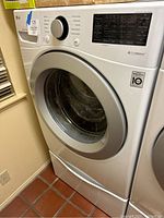 Full frontal and side view of white LG front-loading washing machine on pedestal