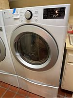 Full front view of LG dryer showing door, control panel and pedestal drawer