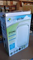 Photo of GermGuardian True HEPA + UV-C Air Purifier box showing product image and features including allergen and odor control, UV-C light technology, and CADR rating.