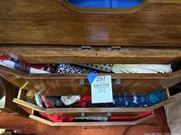 Photo shows wooden drawers partially open with multiple colorful scarves folded inside.