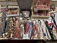 Full spread of bead and pearl necklaces with pendants and box of rings and earrings