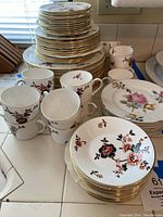 Stacked dinner, salad, bread plates and cups in Khotar floral pattern with gold trim