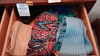 Drawer with beige, multicolored paisley, and light blue ribbed scarves