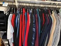 Wide view of multiple women's sweaters hanging on a rack, including assorted colors in red, blue, black, cream, and grey, in various styles.