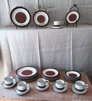 Full set arranged on tabletop and display stands showing dinner plates, salad plates, side plates, cups and saucers in Tan/Rust Potter's Wheel pattern.