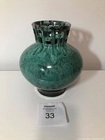 Front and side view of green pottery vase with lattice cut-out neck design, glossy mottled green glaze, bulbous body.