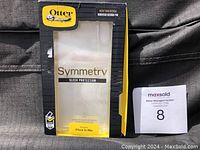 Box front with Otterbox logo, Symmetry Series branding, and clear view of phone case inside showing packaging for iPhone XS Max.