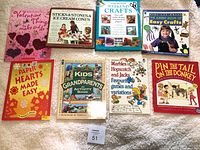 Eight vintage craft and games books arranged on a soft beige surface showing colorful illustrated covers.