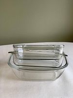 Three clear glass rectangular baking dishes stacked nested inside each other, showing relative sizes and transparency.