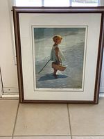 Front view of the framed art print depicting the young girl on the beach, showing the full image and frame.