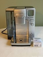 Front view of Cuisinart Keurig coffee maker with water reservoir and digital screen.