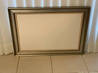 Front view of the empty picture frame showing the metallic finish and white mat board inside.