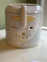 Front view of white Moulinex Supralys deep fryer showing control handle, temperature dial, and power switch