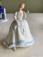 Front view of Royal Doulton Paula figurine showing the woman in a white dress with blue trim and holding a butterfly.