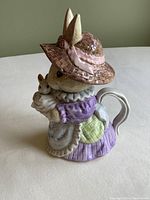 Front angled view of bunny teapot showing mother bunny holding baby bunny, detailed dress and hat.