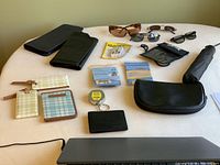 Travel accessories including document organizers, luggage tags, sunglasses, umbrella, and cases arranged on a table.