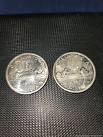 Both Canadian silver dollars dated 1963 and 1965 shown side by side on a black textured background.