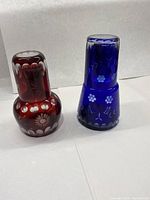 Pair of navy blue and red glass decanters and a matching navy blue tumbler glass. One photo shows the two decanters upside down to highlight the pattern on the base.