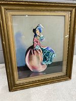 Framed original painting of a woman in a pink dress with blue accents, sitting against a plain background.